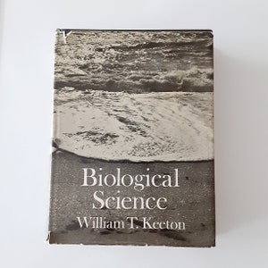 May include: A black and white book cover with a photo of a beach and waves. The title of the book is "Biological Science" by William T. Keeton.