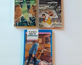 May include: Three vintage paperback mystery books including The Black Spaniel Mystery by Betty Cavanna, The Strange Echo by Frances K. Judd, and Nancy Drew: The Clue in the Antique Trunk by Carolyn Keene, each featuring illustrated covers.