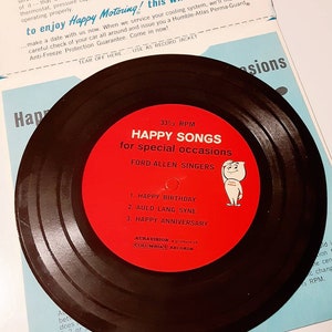 May include: A red and black vinyl record with the text "Happy Songs for special occasions" and "Ford-Allen Singers". The record is a product of Auravision, a product of Columbia Records. The record is 33 1/3 RPM and features three songs: Happy Birthday, Auld Lang Syne, and Happy Anniversary.