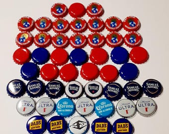May include: A collection of assorted metal bottle caps in red, blue, white, and silver. The caps feature various brand logos and text including Fat Tire, Samuel Adams, Michelob Ultra, Corona Non-Alcoholic, and Dad's Root Beer, arranged in rows.