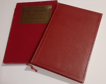 May include: Two red hardcover books with a textured finish. One book features a gold rectangular label on the front cover with the text New Testament, Revised Edition, Revised Standard Version. The other book has a plain red cover and a red ribbon bookmark.