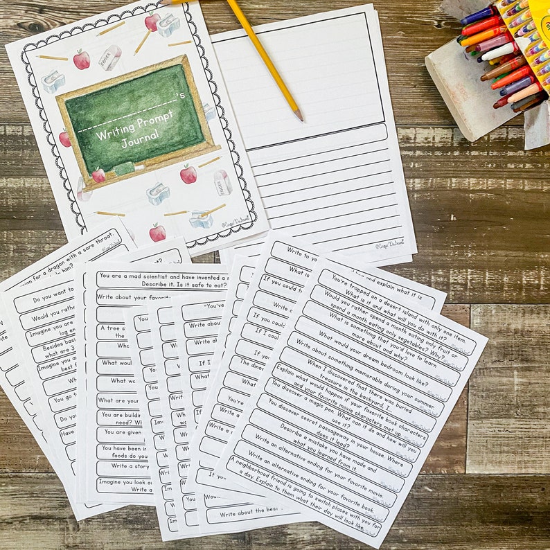 May include: A Writing Prompt Journal with a chalkboard design, pencils, and apples. Includes writing prompt cards and a lined paper sheet. A box of crayons is visible in the background. Educational supplies.