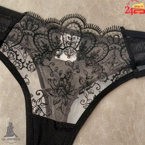May include: Black lingerie with intricate floral lace detailing. The design features a combination of solid black fabric and sheer panels, with delicate lace trim along the edges. The overall aesthetic is elegant and feminine.