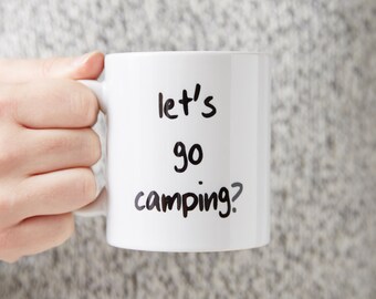以下が含まれることがあります： 白いセラミック製のマグカップに、黒い手書きの文字で「let's go camping?」と書かれています