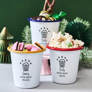 May include: Three white enamelware cups with coloured rims, filled with snacks. Each cup has a popcorn graphic and text: "Emma's Movie Night Snacks", "Dad's Movie Night Treats", and "Dad's Movie Night".