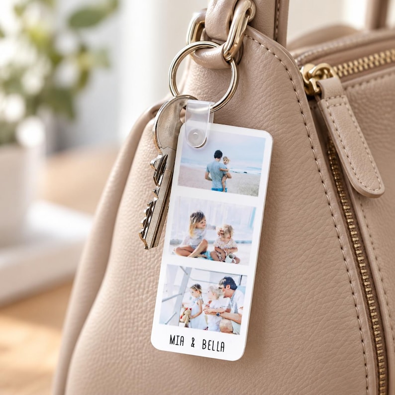 May include: A rectangular white acrylic keyring featuring three stacked photographic prints of children and adults. The keyring is attached to a silver metal ring with a metal key and hangs from a beige leather handbag. The text MIA & BELLA is printed in black at the bottom of the keyring.