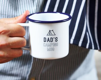 Könnte beinhalten: Weiße Emaille-Camping-Tasse mit blauem Rand und einer schwarz-weißen Grafik eines Zeltes und dem Text "Dad's Camping Mug".