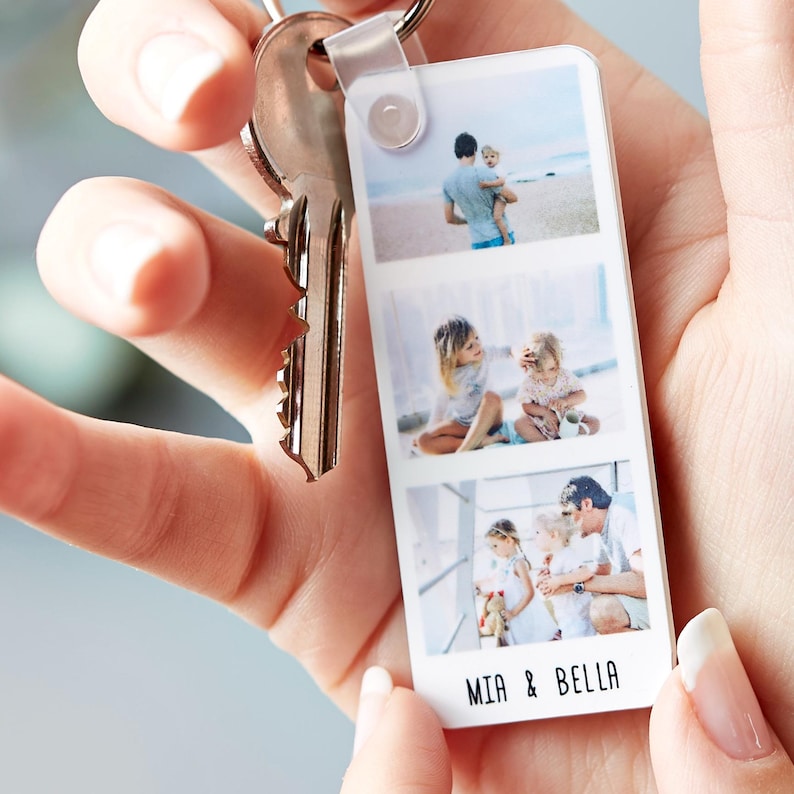 Personalised Photo Strip Keyring with three custom family photos and the names 'MIA & BELLA'; Custom Photo Gift Keyring and Personalized Photo Memory Keychain held in hand with silver key attached.