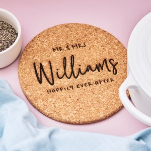 May include: A round cork trivet with the text "Mr. & Mrs. Williams Happily Ever After" engraved in black.
