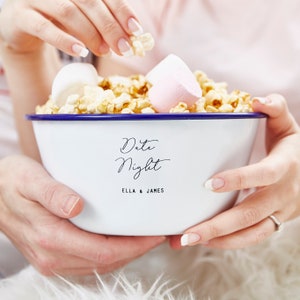 Puede incluir: Tazón de esmalte blanco con borde azul, lleno de palomitas de maíz y malvaviscos. El tazón tiene el texto "Date Night" y "Ella & James" escrito en él.