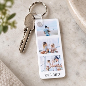 May include: A rectangular white acrylic keyring featuring three stacked horizontal photo prints of a family on a beach and at home. The keyring is attached to a silver metal split ring and includes the printed text MIA & BELLA at the bottom.