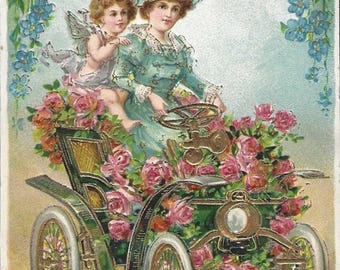 Una dama y un querubín conducen un lujoso coche floral. Postal navideña antigua. Años 1910. Nomeolvides y rosas rosadas con detalles dorados.