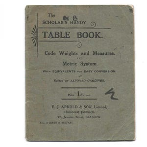 May include: A vintage gray softcover book titled The Scholar's Handy Table Book, Code Weights and Measures, and Metric System, edited by Alfonzo Gardiner. The cover features black printed text, decorative lines, and publisher details for E. J. Arnold & Son.