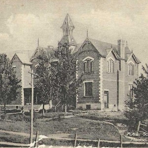 May include: A monochrome postcard depicting a large brick building with multiple gabled roofs, arched windows, and a central tower. Trees and a grassy area surround the building. The text "Public School Madoc" is visible on the bottom right.