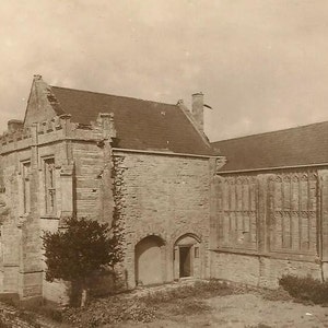 May include: A black and white photograph of a stone building with arched windows and a large doorway. The building appears to be an old church or monastery.