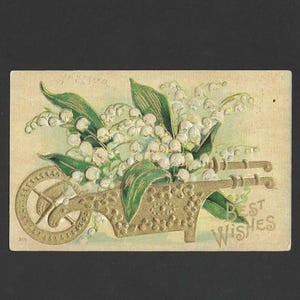 May include: Vintage postcard featuring a wheelbarrow overflowing with white lily of the valley flowers and green leaves. The wheelbarrow is embossed with a gold finish, and the words "Best Wishes" are printed on the card.