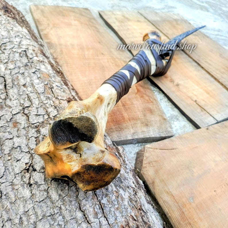 May include: A handmade bone-handled knife with a dark blade. The handle is wrapped in brown leather and white material. The text "marvelousfind shop" is visible on the wooden surface.
