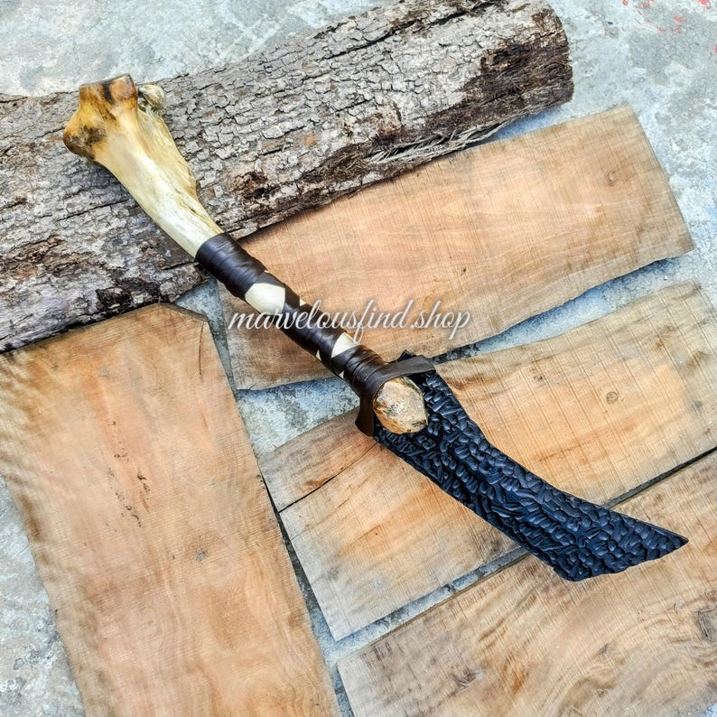 May include: A handcrafted knife with a bone handle and a dark, textured blade. The handle is wrapped with leather and accented with white diamond shapes. The text "marvelousfind shop" is visible.