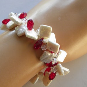 May include: A bracelet featuring square-shaped white pearls and faceted red teardrop beads. The design alternates between the white pearls and the red beads, accented with small, clear, sparkling crystals throughout the piece.
