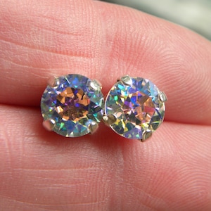 May include: A pair of iridescent silver stud earrings with round, faceted gemstones.