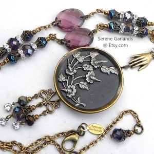 Antique 1870 coat button necklace with Calla Lily or possibly a hibiscus design. The Victorians loved botanicals. Accented with colorful Czech glass in shades of blue-green and amethyst purple with decorative brass. The button is in great condition