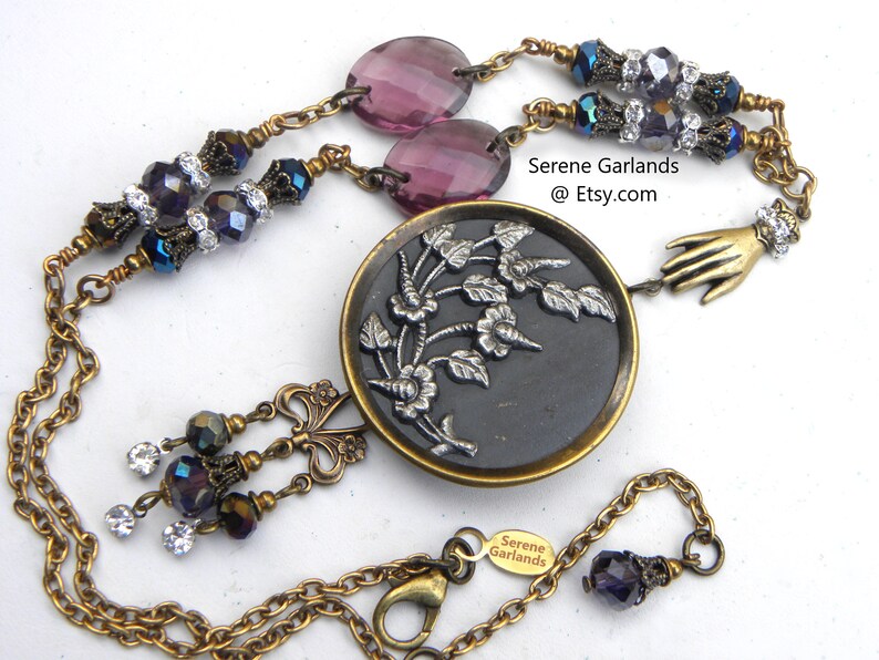 Antique 1870 coat button necklace with Calla Lily or possibly a hibiscus design. The Victorians loved botanicals. Accented with colorful Czech glass in shades of blue-green and amethyst purple with decorative brass. The button is in great condition