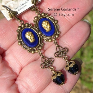 May include: Gold tone earrings with blue cameo pendants and black glass beads. The earrings feature a filigree design and are accented with gold beads.  "Serene Garlands™ @Etsy.com"