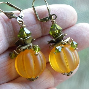 May include: A pair of pumpkin-shaped earrings with green crystal accents and antique bronze findings.