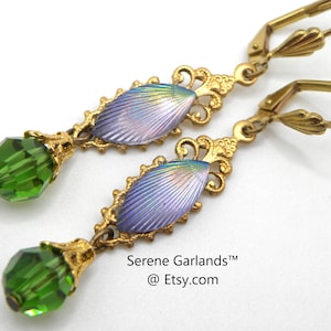 May include: A pair of gold-tone earrings with a purple and iridescent enamel leaf design and a green crystal drop. The earrings have a hook closure.