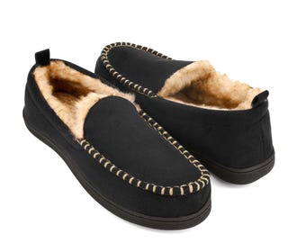 May include: Black suede slippers with a faux fur lining and a brown stitch detail around the edge.