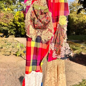 May include: Colorful patchwork pants with a plaid pattern in red, yellow, and purple. The pants feature lace and paisley fabric accents, with a drawstring waist. A unique, handmade garment.