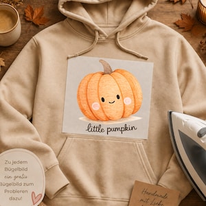 May include: A beige hooded sweatshirt featuring a central graphic of a smiling orange pumpkin with the text "little pumpkin" printed below it. The hoodie has long sleeves, a front kangaroo pocket, and matching beige drawstrings at the neckline.