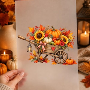 Könnte beinhalten: Ein durchscheinendes Blatt mit einer farbenfrohen Illustration einer hölzernen Schubkarre, gefüllt mit orangefarbenen und weißen Kürbissen, Sonnenblumen, roten Beeren und Herbstblättern. Eine kleine Laterne hängt am Griff und ein rotes Herz ist zu sehen.