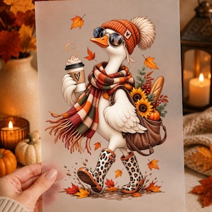 Könnte beinhalten: Ein Druck mit einer weißen Gans, die eine rostorange Strickmütze mit Bommel, eine runde Sonnenbrille und einen karierten Schal trägt. Die Gans hält einen Kaffeebecher mit Herzsymbol, trägt eine braune Tasche mit Sonnenblumen und Brot sowie Stiefel mit Leopardenmuster.