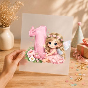 Puede incluir: Una hoja translúcida con una ilustración gráfica del número uno en rosa brillante, decorado con una mariposa, flores rosas y blancas y una seta, junto a un hada de cabello rubio, corona de flores y alas de colores claros.