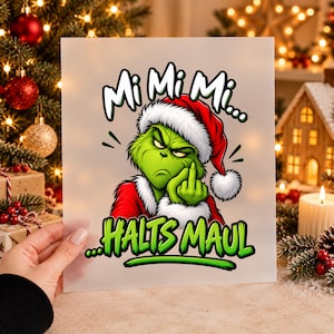 Könnte beinhalten: Ein quadratischer Druck mit einer grünen, pelzigen Figur in einer rot-weißen Weihnachtsmütze, die eine unhöfliche Geste macht. Der Text Mi Mi Mi steht über der Figur, und der Text HALTS MAUL ist in grüner Farbe unter dem Bild gedruckt.