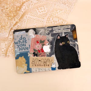 May include: Laptop skin featuring a black cat illustration with yellow eyes, surrounded by stickers and text. The skin has a collage design with floral and cat-themed elements, including the text "do what you love!"
