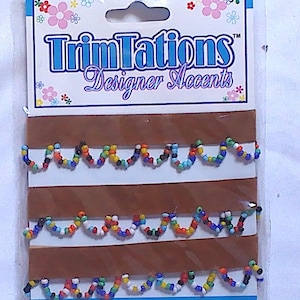 May include: A package of TrimTations Designer Accents trim. The trim is a wavy design of colorful beads on a brown and white backing. The trim length is 18 inches.
