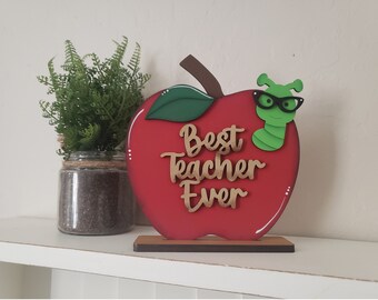 May include: Red wooden apple with a green worm wearing glasses and the words "Best Teacher Ever" in gold lettering.