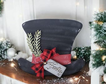 May include: Black and red snowman hat with a green sprig, a red and black plaid bow, and a tag that says "Frosty".
