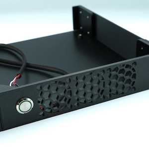 Könnte beinhalten: Schwarzes Server-Rack-Bauteil mit wabenförmiger Belüftung und einem Power-Knopf. Das Rack hat Befestigungslöcher an der Vorder- und den Seiten. Ein schwarzes Kabel mit roten, weißen und schwarzen Drähten ragt aus dem Inneren heraus.