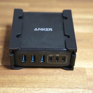 May include: Black Anker charging station with multiple USB ports. The device has the brand name "ANKER" printed on the top. It features several USB ports with blue interiors and additional ports labeled "30W" and "IQ".
