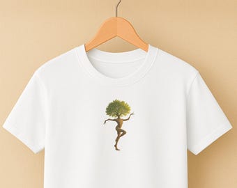 Puede incluir: Camiseta blanca con un diseño único de una figura humana con una cabeza de árbol. La figura está en una pose de baile, con los brazos extendidos. La obra de arte utiliza tonos marrones y verdes.