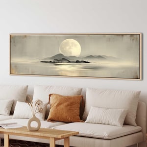 Könnte beinhalten: Ein rechteckiger, gerahmter Leinwandkunstdruck zeigt eine ruhige Landschaft. Ein großer, heller Vollmond dominiert den Himmel über silhouettierten Bergen und einem ruhigen Gewässer. Die Farbpalette ist gedämpft, mit weichen Grau-, Weiß- und Beigetönen.