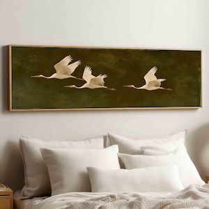 Könnte beinhalten: Ein rechteckiges Wandbild mit drei fliegenden weißen Kranichen vor einem dunkelolivgrünen Hintergrund, eingefasst in einen dünnen goldenen Rahmen. Die Vögel sind mit ausgebreiteten Flügeln horizontal auf der Leinwand dargestellt.