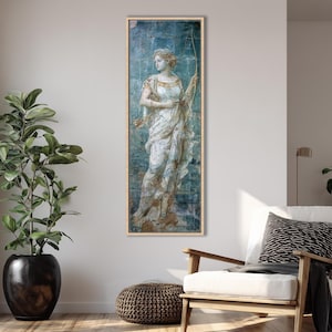 May include: A vertical rectangular wall art print featuring a classical painting of a figure in a draped white gown holding a long bow. The artwork has a distressed blue and gold textured background, framed in a light-colored wooden frame.