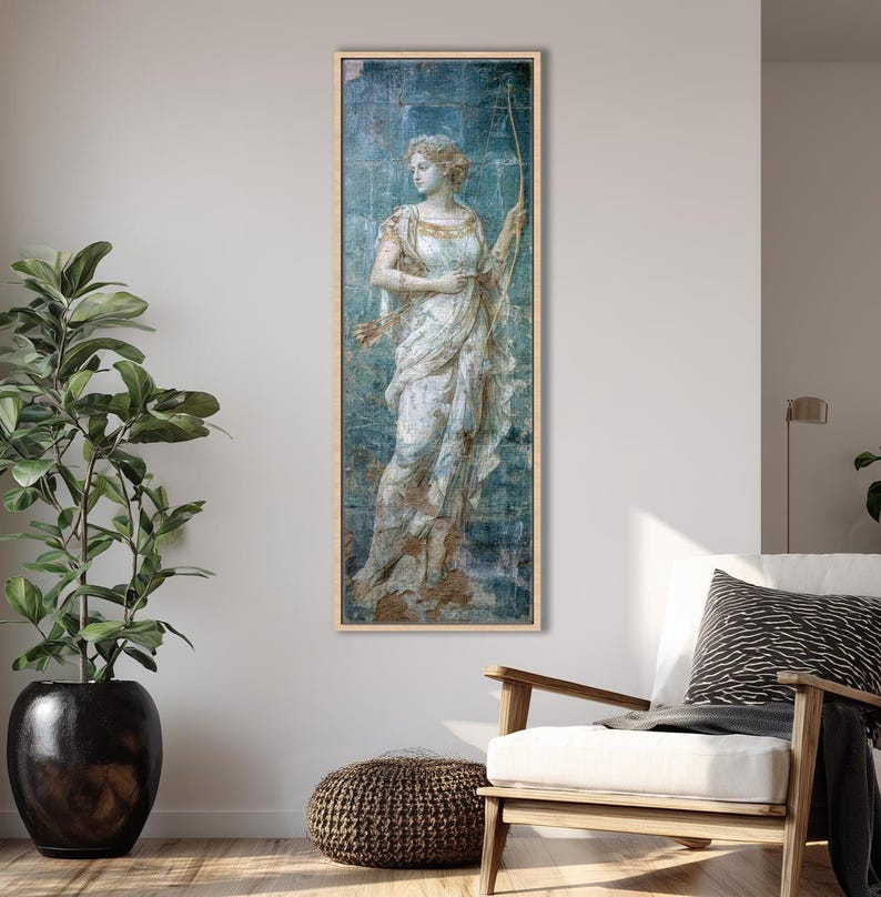 May include: A vertical rectangular wall art print featuring a classical painting of a figure in a draped white gown holding a long bow. The artwork has a distressed blue and gold textured background, framed in a light-colored wooden frame.