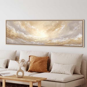 May include: A panoramic rectangular wall art piece featuring an abstract landscape with swirling clouds and textured waves in shades of cream, beige, white, and metallic gold, enclosed within a thin, light-toned wooden frame.