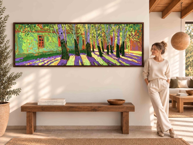 Puede incluir: Un cuadro panor&aacute;mico de paisaje en un marco de madera oscura que muestra una hilera de &aacute;rboles con hojas verdes y troncos oscuros que proyectan largas sombras p&uacute;rpuras sobre un suelo amarillo brillante, junto a un edificio verde con marcos rojos.