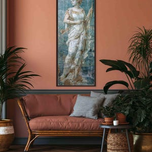 May include: A vertical rectangular framed wall art print featuring a classical figure in a flowing white draped garment, holding a long bow. The artwork has a weathered, distressed texture with blue and gold tones, set against a solid dark frame.